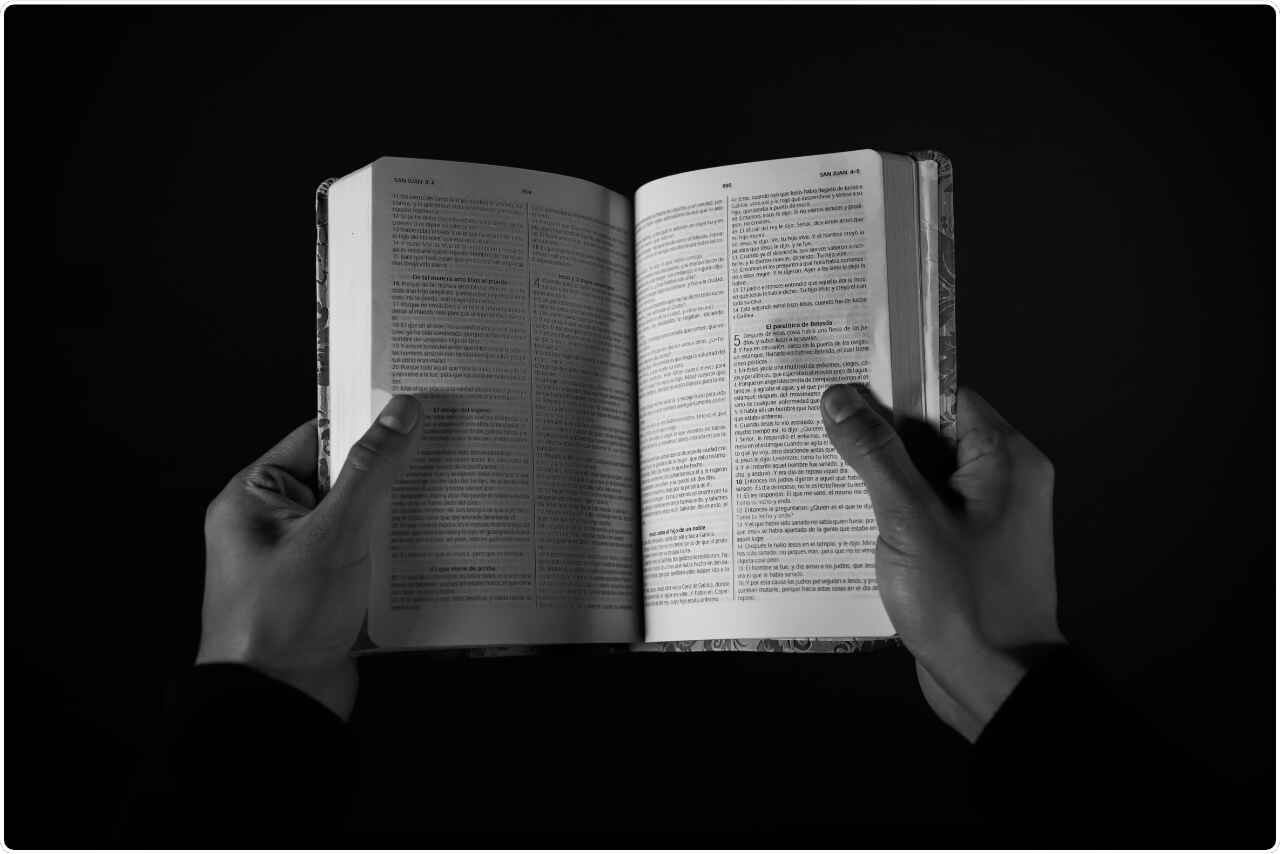 Black and white image of a person with a book in their hands.